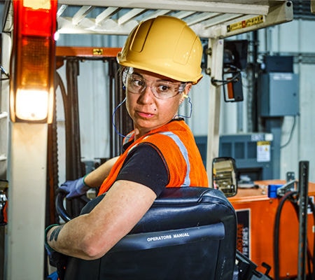 Person driving forklift in warehouse wearing J.J. Keller SAFEGEAR PPE