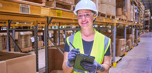 Person in warehouse smiling and taking inventory 